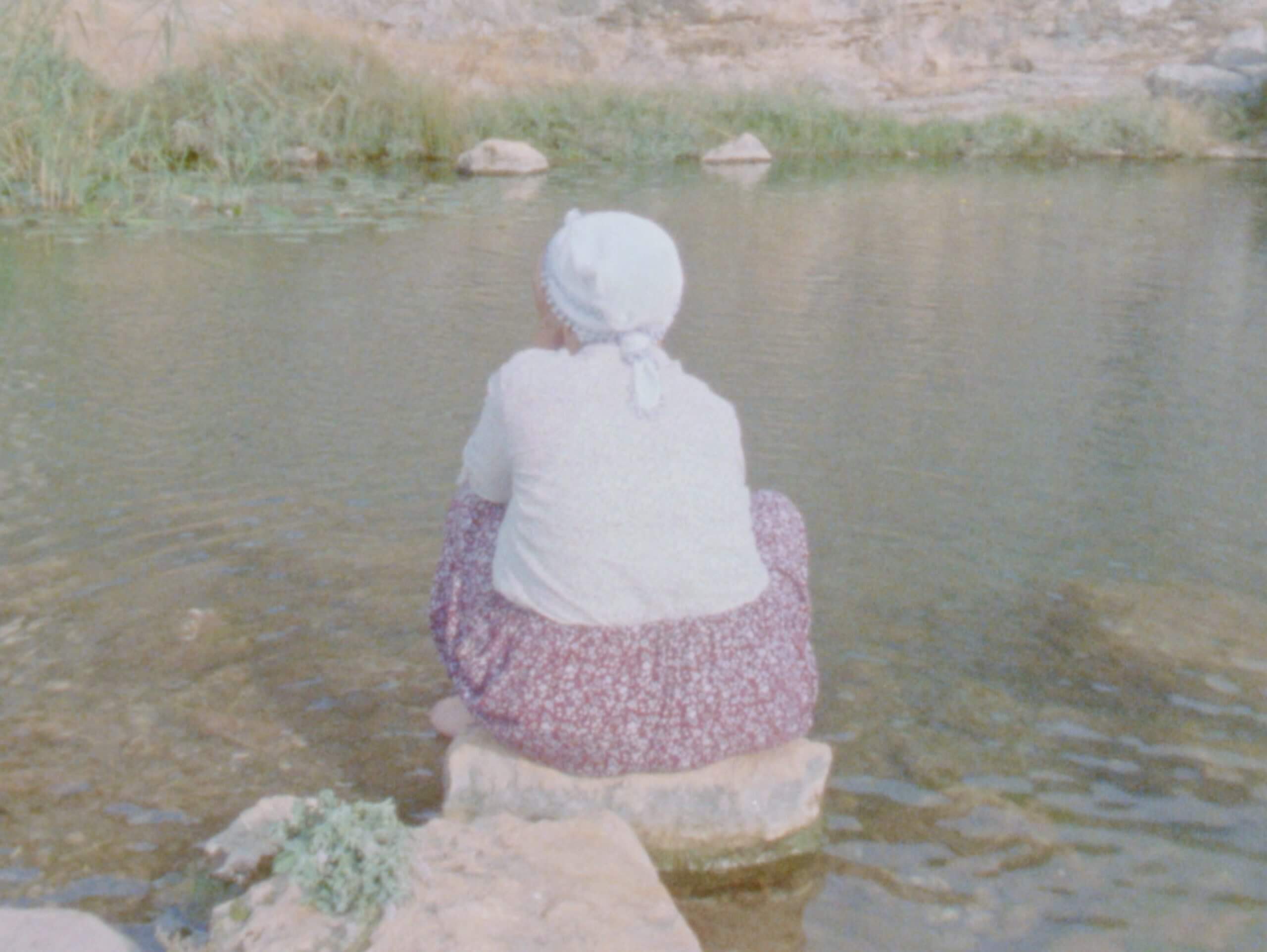 Une femme kurde assise sur la berge d'une rivière dans le film Ever Since, I've Been Flying