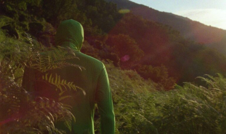 Une personne dans la jungle vêtue d'un green screen suit dans une scène du film The Invisible Mountain