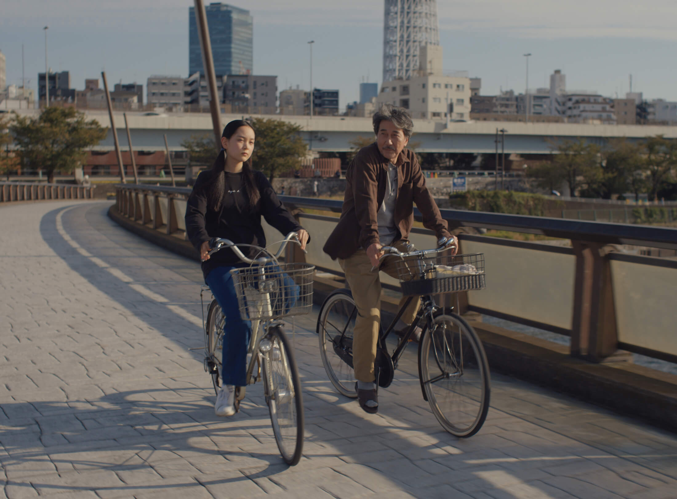 Koji Yakusho et Arisa Nakano à vélo dans une scène du film Les jours parfaits