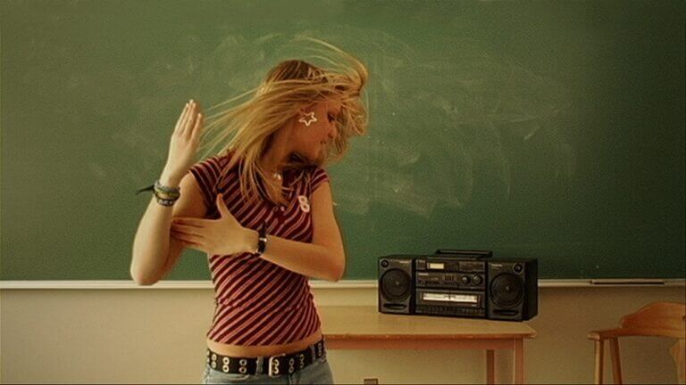 Une adolescente danse dans une salle de classe dans une scène du film À l'ouest de Pluton