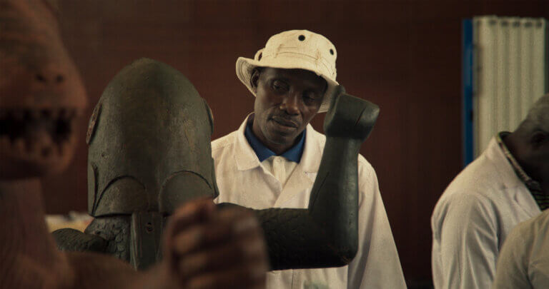 Un homme observe une sculpture dans une scène du film Dahomey.