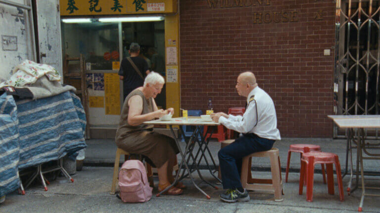 Une femme occidentale et un agent de sécurité hongkongais dînent devant un restaurant dans une scène du film Wood and Water.