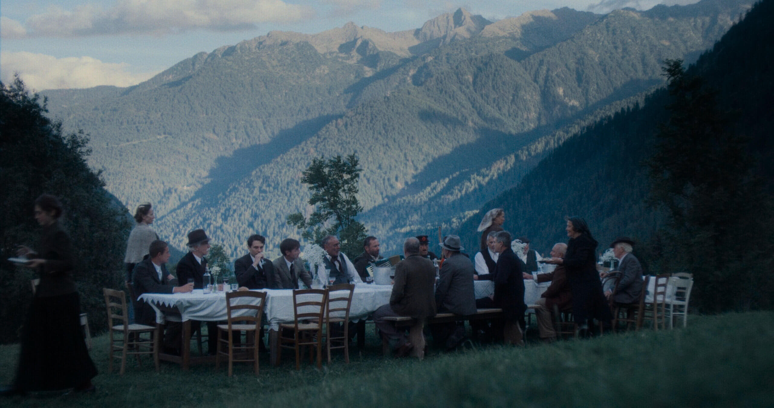 Un banquet avec un spectaculaire paysage montagneux en arrière-plan dans une scène du film Vermiglio.