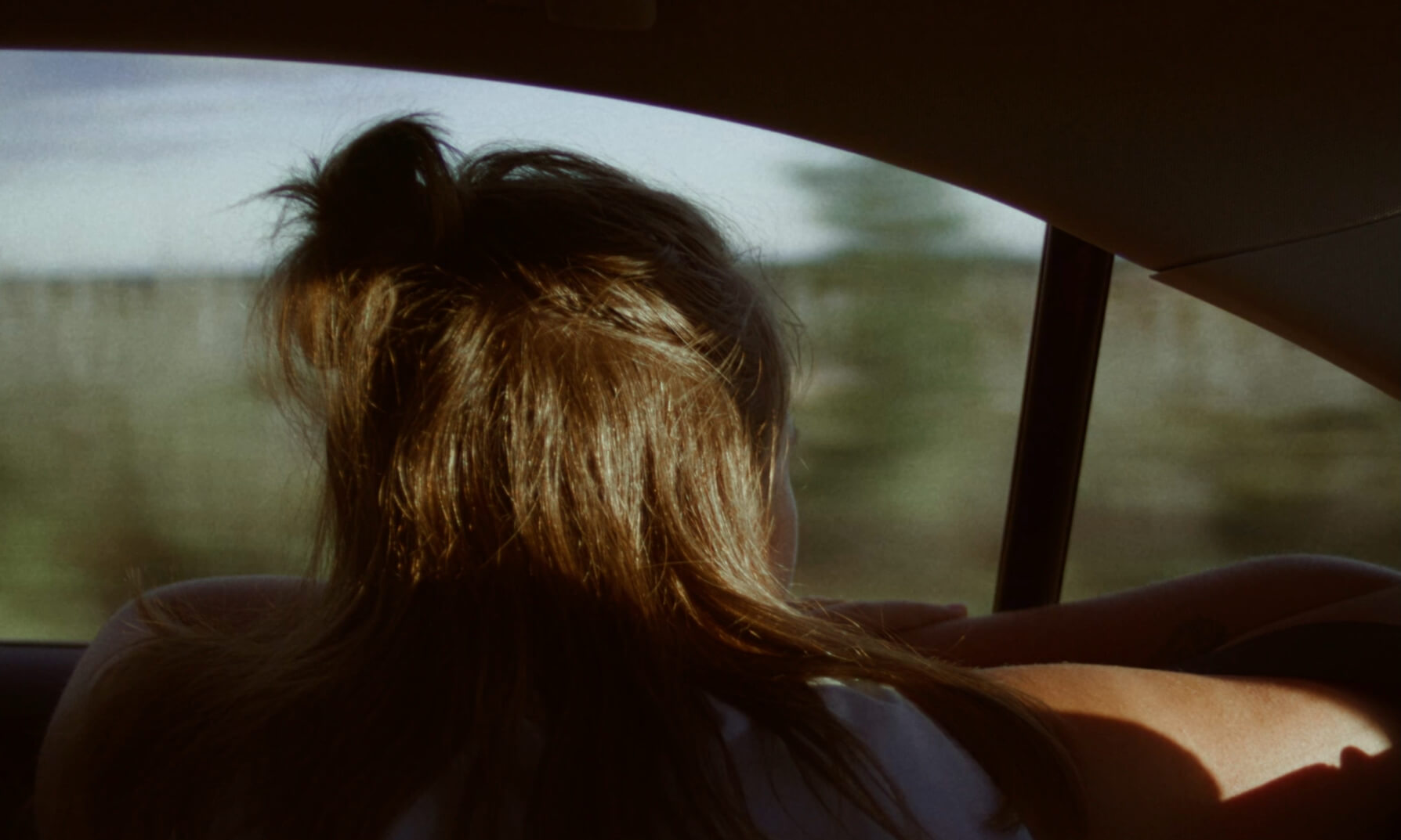 Une personne vue de dos dans une voiture en mouvement dans une scène du film Jamais nulle part.