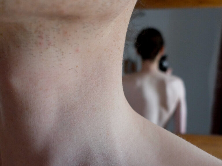 Un jeune homme torse nu prend une selfie sans révéler son visage. Son reflet apparaît en arrière-plan.