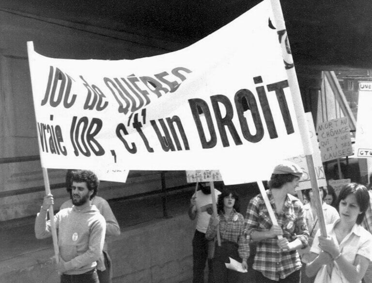 Des manifestants de la Jeunesse Ouvrière Catholique brandissent une bannière sur laquelle on peut lire : « JOC de Québec - Une vrai job, c't'un droit ».