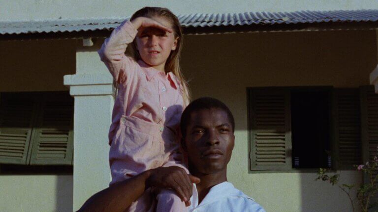 Une petite fille blanche assise sur l'épaule d'un jeune homme noir.